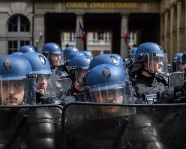 Un grupo de gendarmes con cascos azules y escudos protectores se prepara para mantener el orden frente al Conseil Constitutionnel.