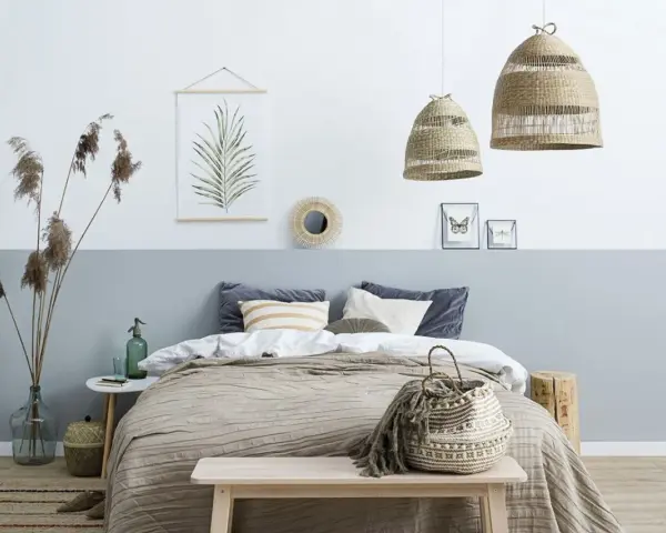 Sypialnia z łóżkiem i dwukolorową ścianą, pokazującą, jak połączyć dwa kolory na jednej ścianie. Wnętrze w stylu boho.