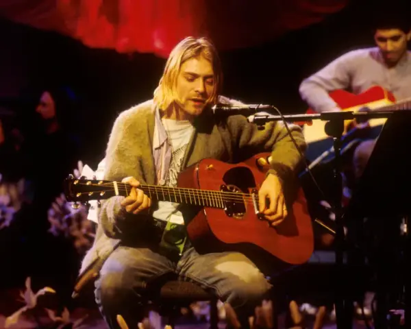 Kurt Cobain gra na gitarze akustycznej, czuć atmosferę, która pachnie nirvaną.