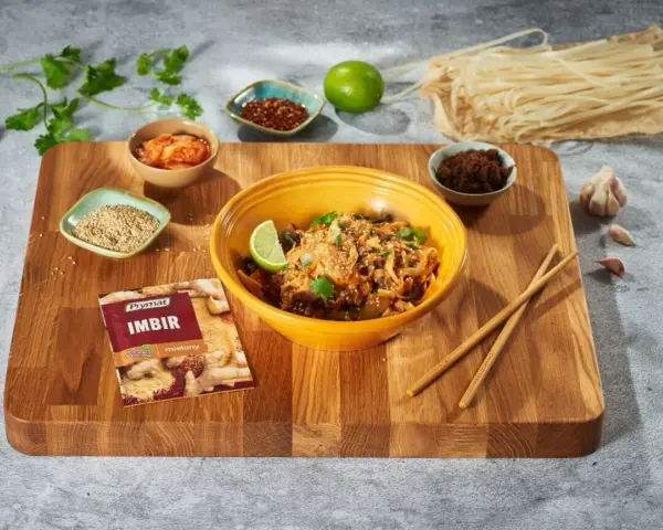 Curry z kurczakiem czy stir-fry z wołowiną? Na desce składniki do dania z makaronem ryżowym, imbir, sezam, chili, czosnek i limonka.