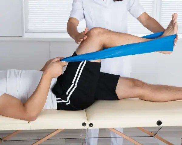 Therapeut dehnt Bein mit blauem Band zur Behandlung von Plica-Syndrom, inspiriert von Liebscher & Bracht Methoden.