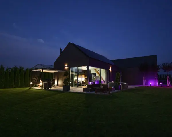 Nowoczesny dom nocą, z oświetlonym ogrodem i tarasem. Analiza prawdziwych kosztów eksploatacji domów pasywnych w polskich warunkach klimatycznych.
