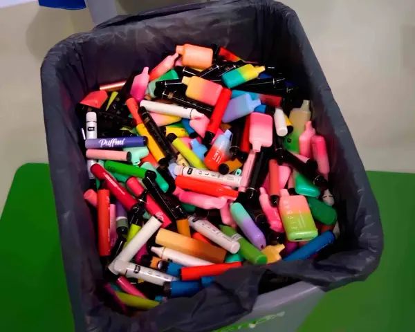 Contenedor lleno de vapes desechables de colores. ¿Qué hacer con un vape desechable? Reciclaje responsable.