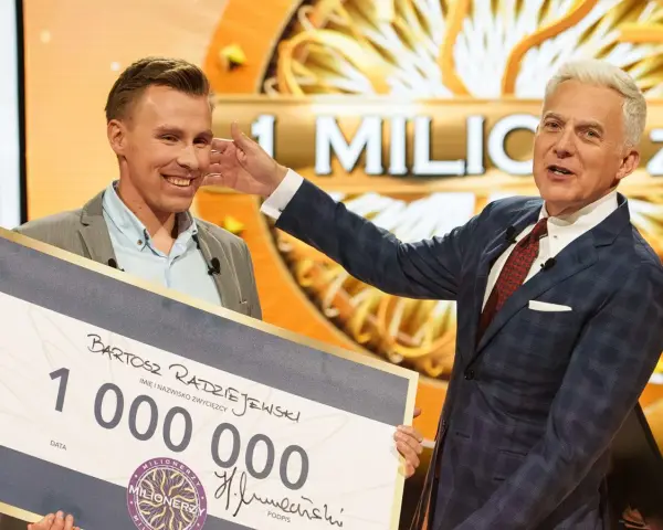 Bartosz Radziejewski, który wygrał milion w Milionerach, odbiera czek z nagrodą od Huberta Urbańskiego.