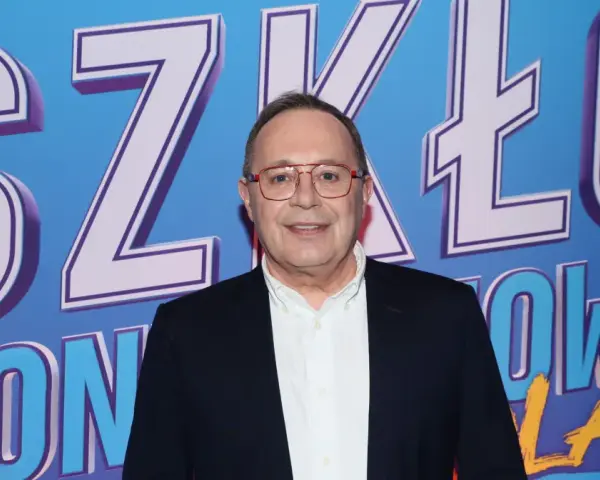 Uśmiechnięty mężczyzna w okularach na tle napisu "SZKŁO KONTAKTOWE OBSADA".