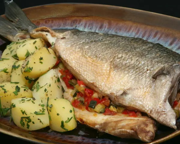 Lubina al horno con verduras y patatas. Un plato principal delicioso y saludable.