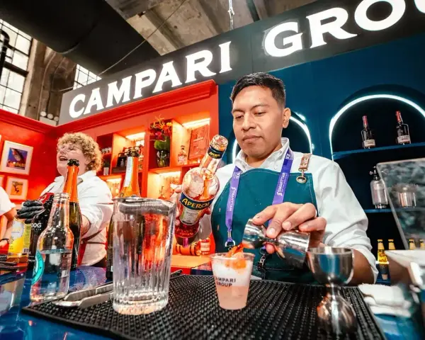 Barman nalewa Aperol do drinka, w tle logo Campari.
