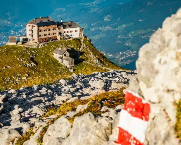 Watzmannhaus Wanderung: Ein markierter Weg führt zu diesem Berggasthof auf einem felsigen Grat mit Blick ins Tal.