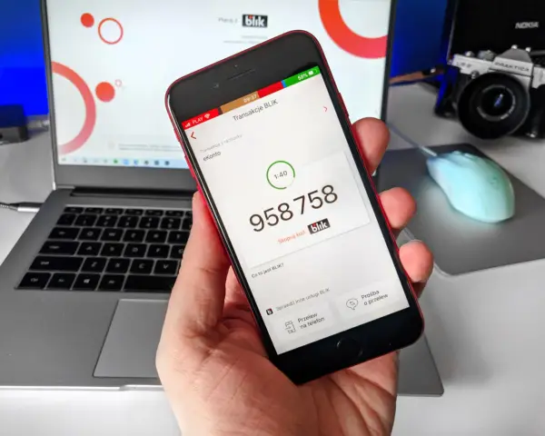 Dłoń trzyma smartfon z aplikacją Blik, na ekranie widoczny kod transakcji.