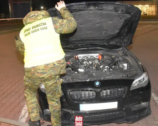 Funkcjonariusz Straży Granicznej sprawdza silnik BMW, wykonując rozkodowanie VIN.
