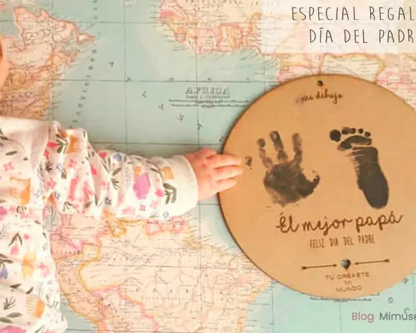 Manualidad Día del Padre 2 años: huella de mano y pie de bebé en un círculo de cartón sobre un mapa.