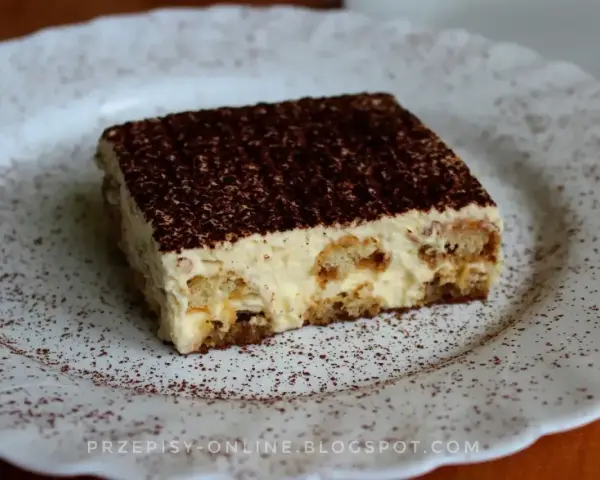 Pyszne tiramisu, czyli zabajone, na białym talerzu, posypane kakao.