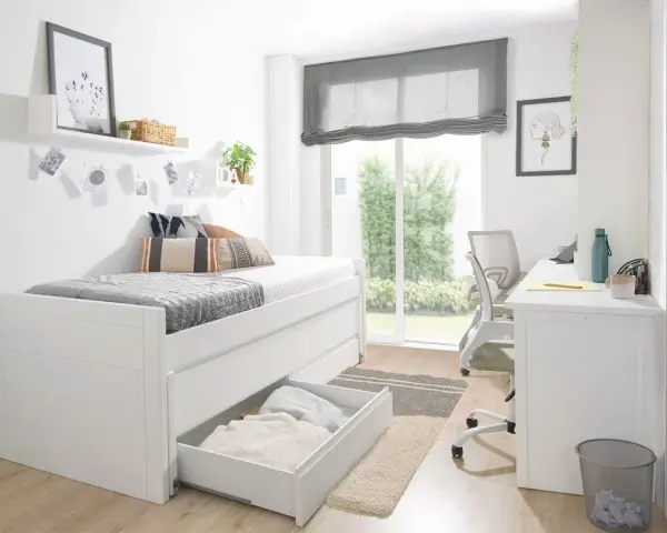 Habitación estrecha y alargada con cama blanca, escritorio y silla. Ventana grande con vistas al jardín.