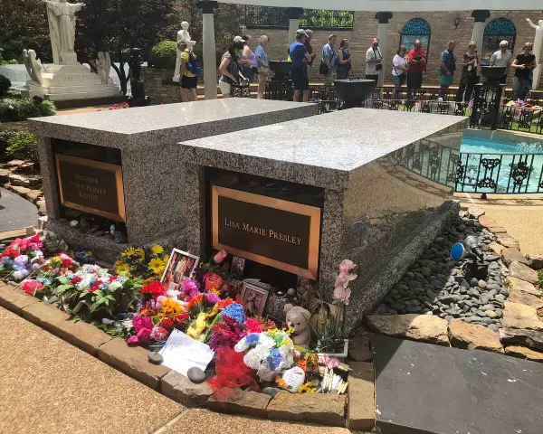 Gräber von Lisa Marie und Benjamin Keough, umgeben von Blumen. Viele Besucher ehren das Erbe von Elvis Presley.
