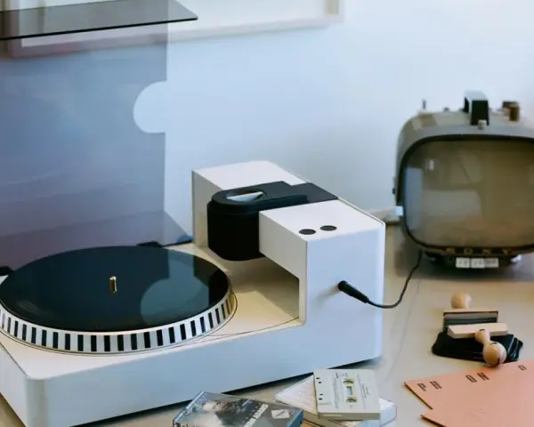Moderner Plattenspieler mit Vinyl-Schallplatte, Kassetten und Retro-Fernseher. Hier wird die Frage "was ist Vinyl Musik" visuell beantwortet.
