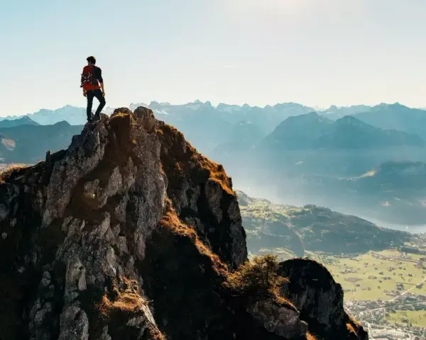 Wspinacz na szczycie skalistej góry, podziwiający panoramę gór i doliny. To jest wejście na Rysy.