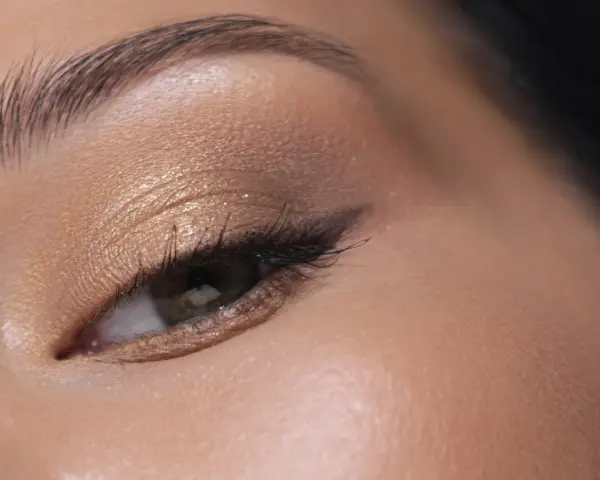 Maquillage paupière tombante : ombre dorée scintillante, trait d'eye-liner fin et cils longs pour un regard sublimé.