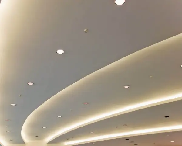 Nowoczesny podwieszany sufit z ukrytym oświetleniem LED tworzy łagodne, faliste linie, dodając przestrzeni elegancji.
