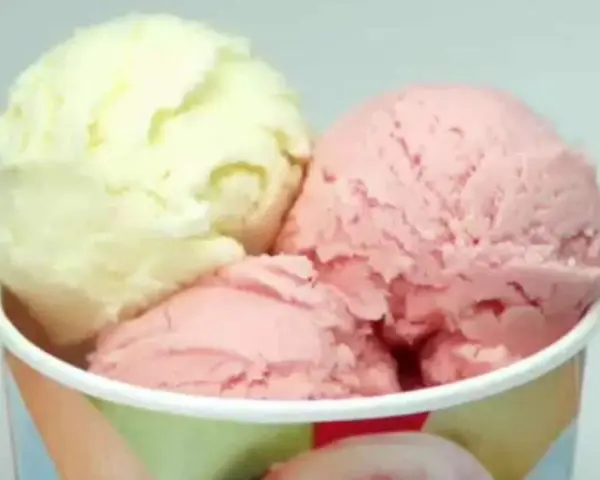 Drei Kugeln Eis in einem Becher: eine hellgelbe und zwei rosafarbene. Verschiedene eis arten für süße Momente.