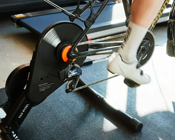 A cyclist's feet pedal on a bike connected to a magnetic resistance trainer, ready for an indoor workout.
