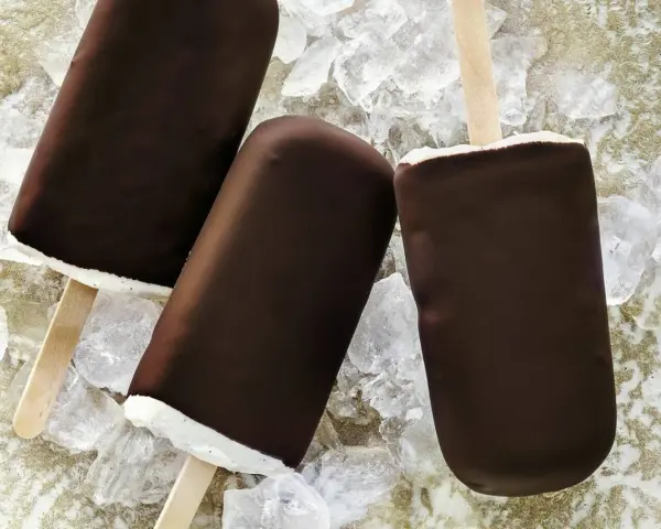 Drei Schokoladen-Vanilleeis am Stiel liegen auf Eiswürfeln.