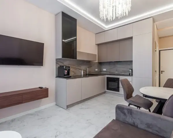 Un moderno open space lungo e stretto con cucina a vista, zona TV e tavolo da pranzo.