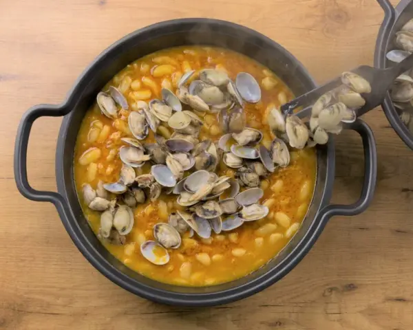 Plato humeante de fabes con almejas, un manjar tradicional.