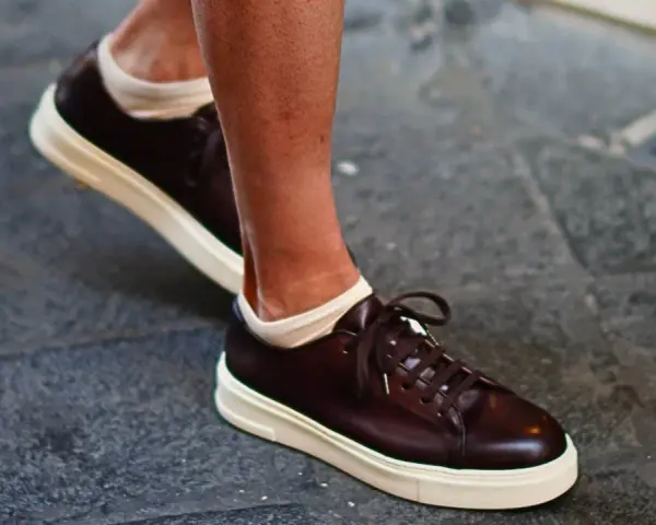 Un uomo indossa sneakers marroni con calze bianche a vista. Un look casual ma curato, perfetto per chi cerca quali calze con sneakers uomo.