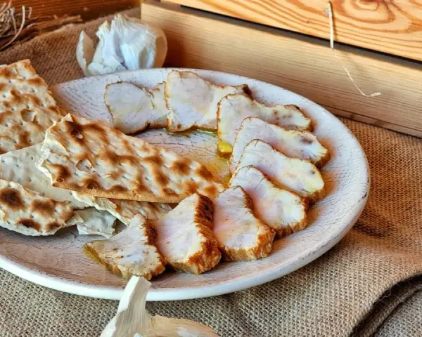 Lomo de orza en rodajas, servido con pan crujiente y ajo. Un plato rústico y delicioso.