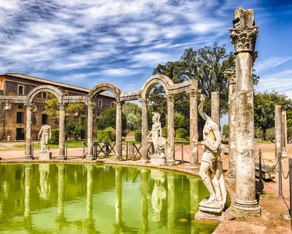 Starożytne ruiny i rzeźby w Villa d'Este odbijają się w zielonym stawie.