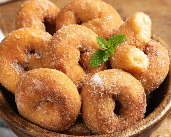 Rosquillas de la abuela esponjosas, cubiertas de azúcar y canela, con una ramita de menta. ¡Un placer casero!