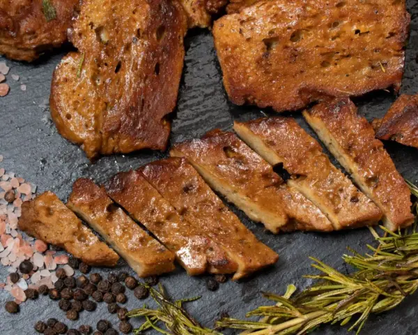 Pokrojony seitan, przypominający mięso, z rozmarynem i solą. To świetna alternatywa dla mięsa, jeśli zastanawiasz się, seitan co to.