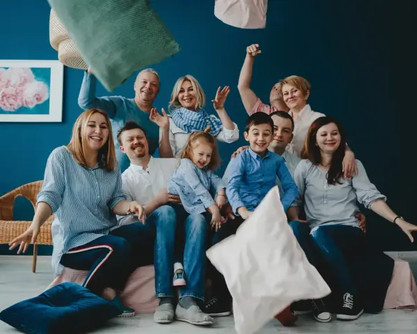 Wesoła rodzina patchworkowa rzuca poduszkami, śmiejąc się i ciesząc wspólnym czasem.