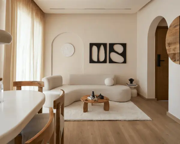 Un soggiorno in stile wabi sabi arredamento, con divano curvo, tavolino in legno grezzo, tappeto soffice e decorazioni organiche.