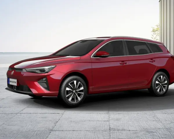 Czerwony MG5 Electric, kombi, stoi na betonowym placu z widokiem na morze.