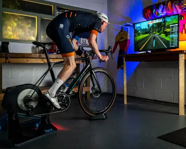 A cyclist trains indoors on a bike trainer, with a screen showing a virtual road. This setup demonstrates how to set up a bike trainer for immersive cycling.