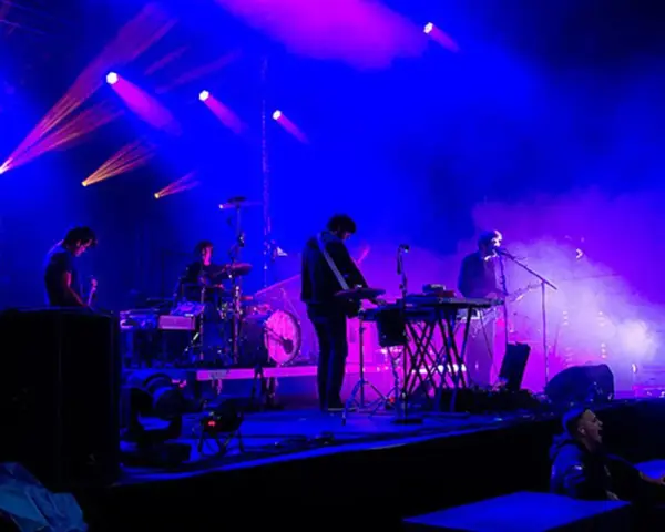 Un groupe allemand des années 2010 joue sur scène sous des lumières bleues et violettes.