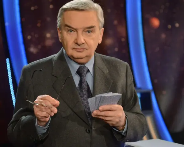 Starszy mężczyzna w garniturze trzyma okulary i karty z napisem "jeden z dziesięciu kiedy".
