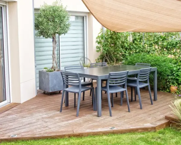 Terrasse mit Tisch und Stühlen, Sonnensegel und üppiger Bepflanzung. Tolle selber balkon sichtschutz ideen für Privatsphäre.