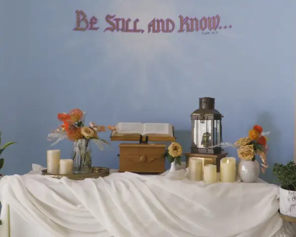A serene scene for a midnight vigil: an open Bible, a lantern, and candles on a draped table, with "Be Still, and Know..." on the wall.
