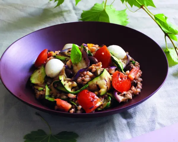 Insalata di farro estiva con verdure grigliate, pomodorini, mozzarelline e basilico fresco.