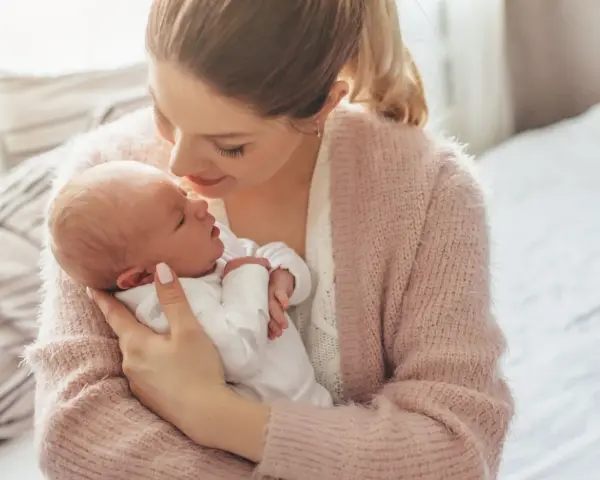 Delikatna pozycja do odbijania noworodka w ramionach mamy, która tuli go z miłością.