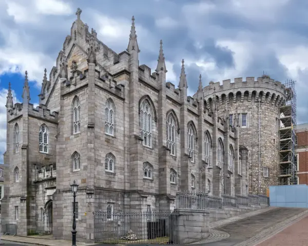 Kamienne mury i strzeliste wieże zdobią zamek w Dublinie. Gotycka architektura i chmurne niebo tworzą majestatyczny widok.
