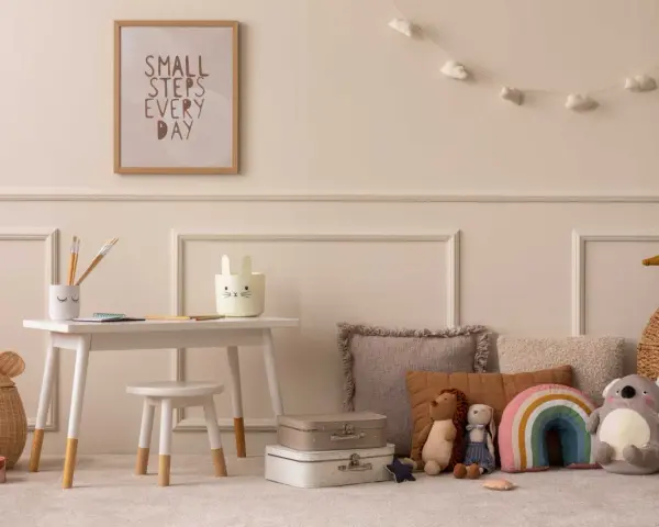 Ein Kinderzimmer mit einem kleinen Schreibtisch, Spielzeug und einem Bild mit der Aufschrift "Small steps every day". Eine beige Mom würde sich hier wohlfühlen.