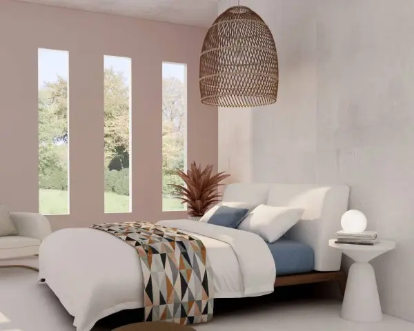 Habitación con cama blanca y manta geométrica. Tres ventanas verticales dejan ver un jardín. El espacio, con tonos neutros, evoca la serenidad de los cuartos blancos.