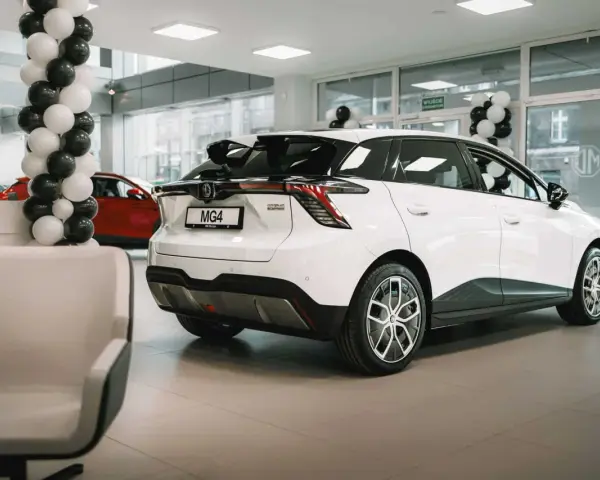 Biały samochód MG4 Electric prezentowany w salonie, ozdobionym czarno-białymi balonami.