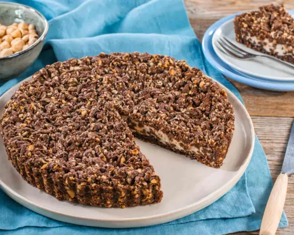 Sbriciolata ricotta e cioccolato con croccante copertura di nocciole. Una fetta invitante attende su un piattino.