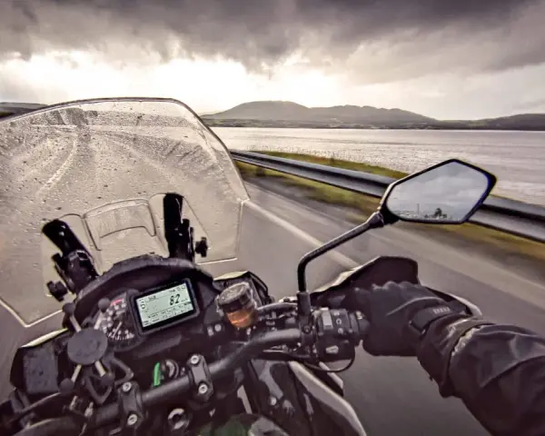 Jazda motocyklem w deszczu w kierunku Nordkapp. Pochmurne niebo i mokra droga nie zniechęcają do podróży.