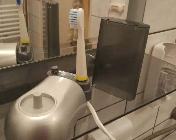 Pierwsze ładowanie szczoteczki elektrycznej. Nowa szczoteczka z ładowarką i etui na półce w łazience.