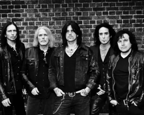 Les membres de Black Star Riders posent devant un mur de briques.